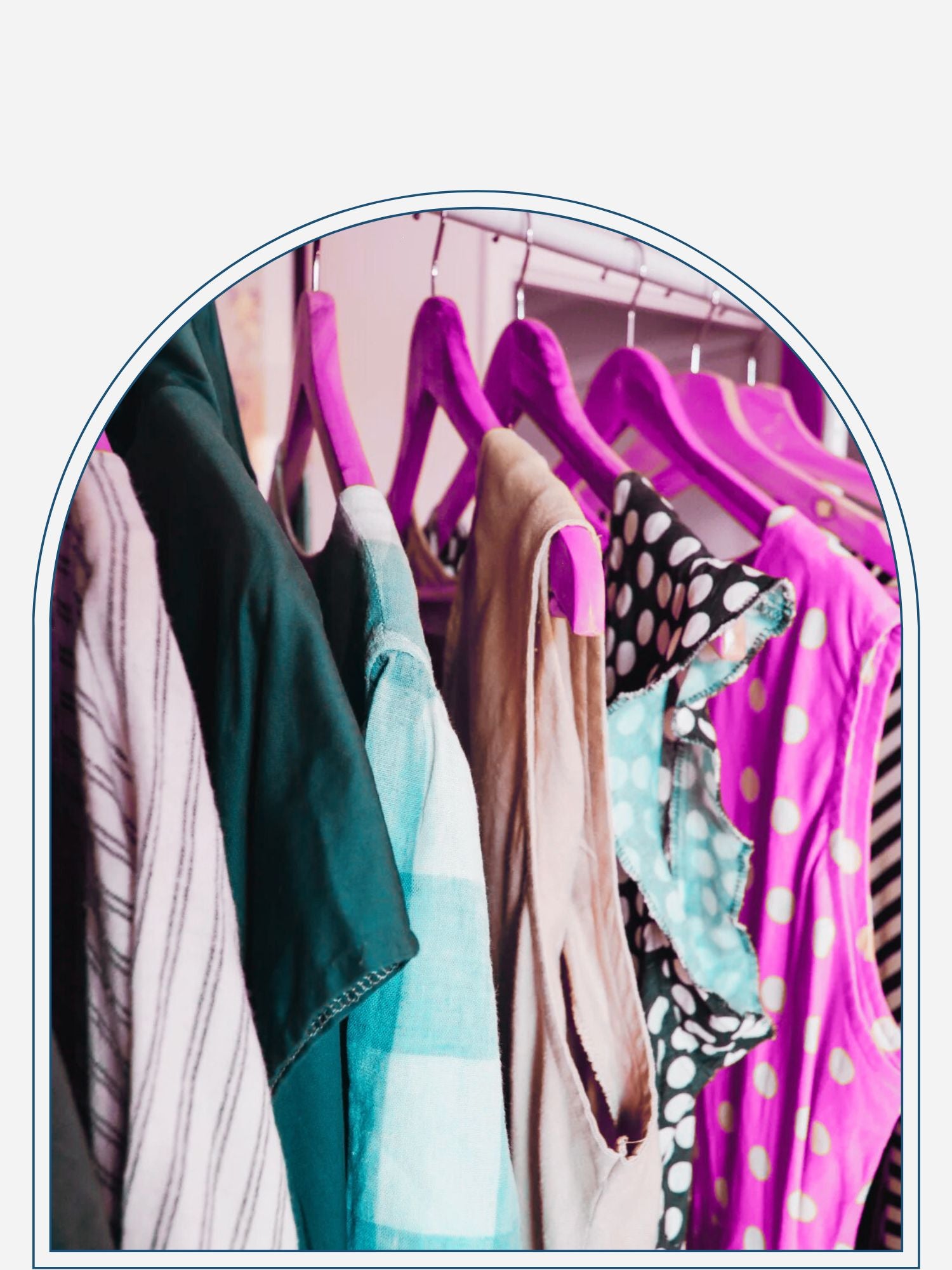 A selection of custom-made clothing items displayed on wooden hangers, including a green skirt, a white and purple shirt, and an orange top with polka dots.