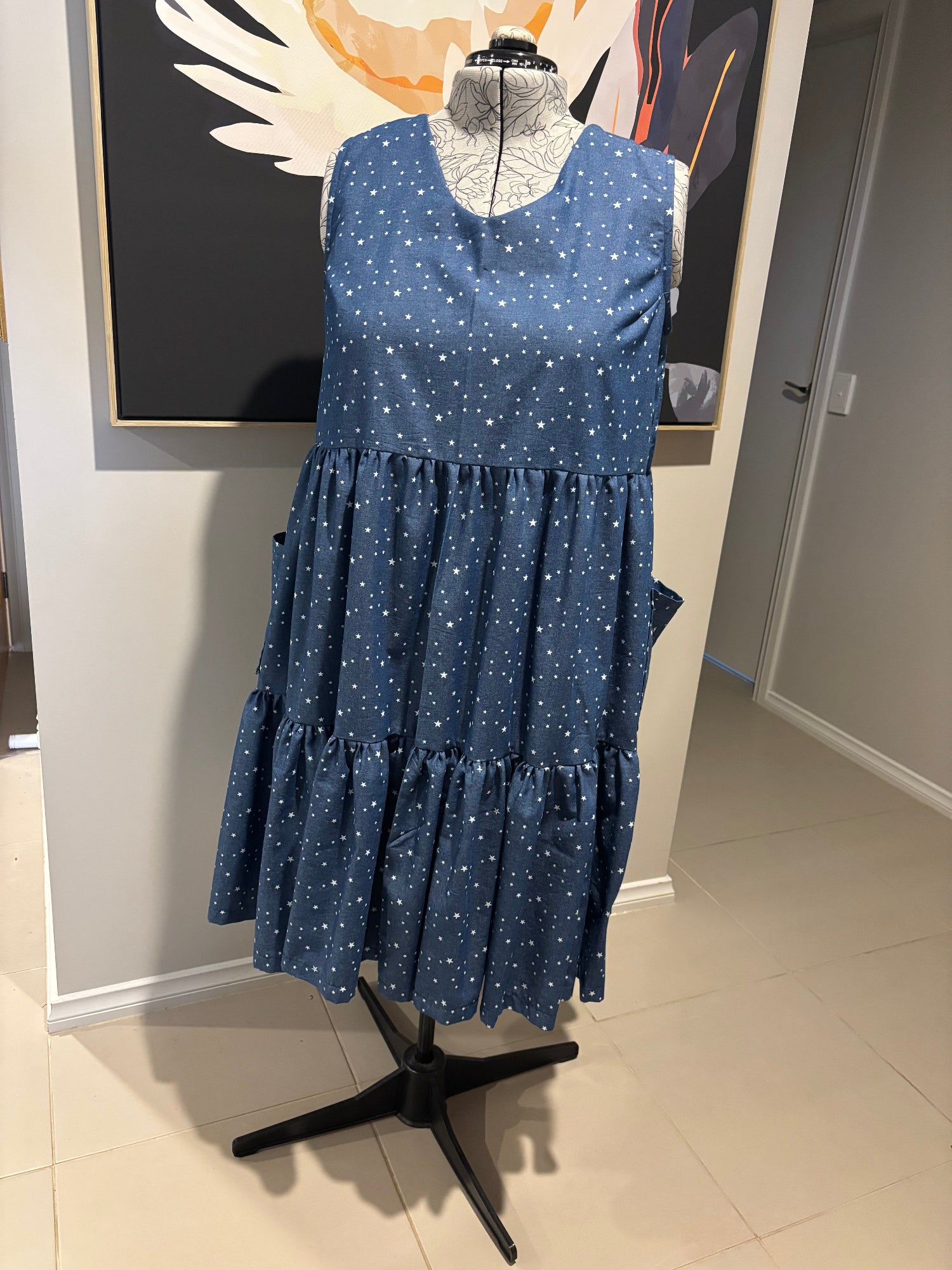 Blue dress with white stars on a mannequin against a neutral background