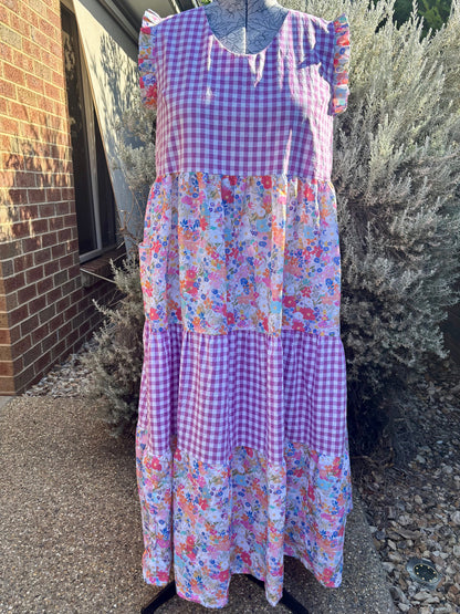 A floral tiered dress displayed on a mannequin, with pockets, against an outdoor background.